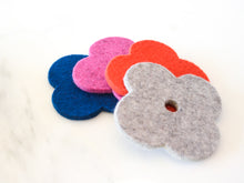 White background with four colorful flower coasters laid out in colors red, pink, navy and grey. The coasters are made of 1/4" thick wool felt and have a slight textured appearance.