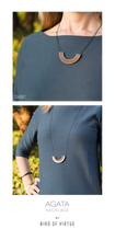 On model shot of Agata Necklace in walnut wood and rose gold. Model is wearing navy blue shirt with greenery behind and image shows the necklace being worn short as well as long.