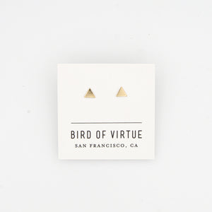 Tiny gold triangle stud earrings on white Bird of Virtue card, on white background