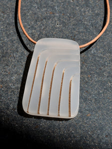 Rectangular gray pendant with curved arch gold lines on leather cord necklace, photographed on black stone surface