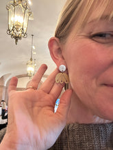 Woman with hair pulled back wearing silver and gold floral earring