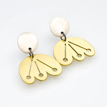 Pair of earrings with gold and white components on a light gray background