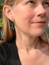Black oval earring with silver geometric lines worn by a blonde woman in a black top – a striking contrast against her hair. Made by Bird of Virtue - San Francisco, CA