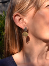 Close-up of a person wearing brass earrings with a blurred background