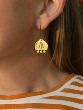 Brass earring worn by a person with a striped shirt