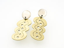 Brass earrings with wavy designs on a white background