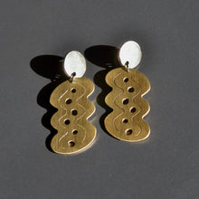 Pair ofbrass and silver earrings on a dark gray background