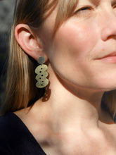 Close-up of a woman wearing a unique earring with wavy lines and circles.