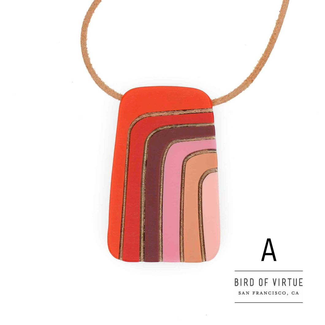 Bright orange pendant with burgundy, pink and peach curved stripes highlighted by gold on leather necklace.