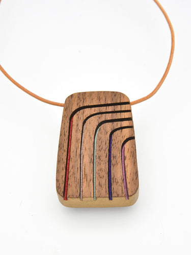 Wooden pendant with inlaid lines on a white background by Bird of Virtue