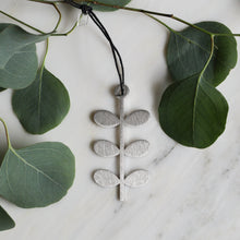 Brushed stainless steel modern flower metal ornament with geometric leaf tiers, Scandinavian design, on hemp cord