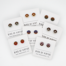Various circular wooden stud earrings with colorful concentric circle designs on Bird of Virtue display cards from San Francisco.
