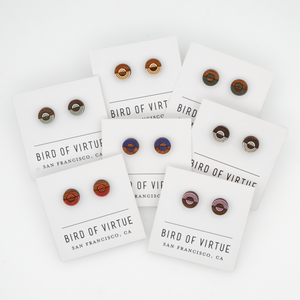 Various circular wooden stud earrings with colorful concentric circle designs on Bird of Virtue display cards from San Francisco.