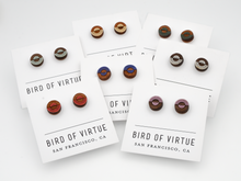 Various circular wooden stud earrings with colorful concentric circle designs on Bird of Virtue display cards from San Francisco.