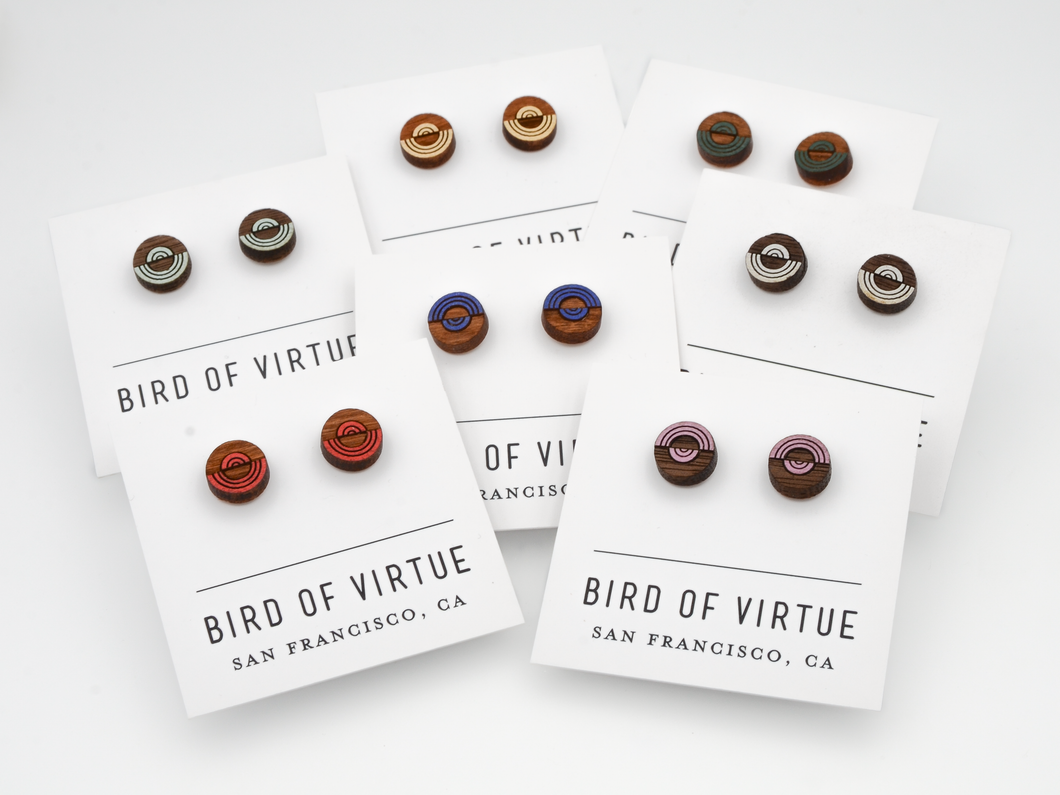 Various circular wooden stud earrings with colorful concentric circle designs on Bird of Virtue display cards from San Francisco.