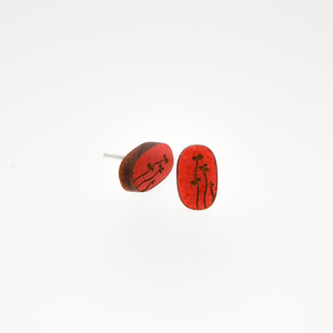 Close-up of a red oval wooden earring with a simple black plant design on a white background. 