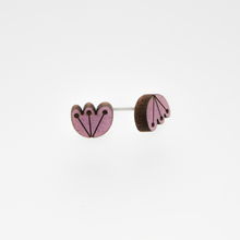 One pair of orchid colored stud earrings with floral designs on a white background.