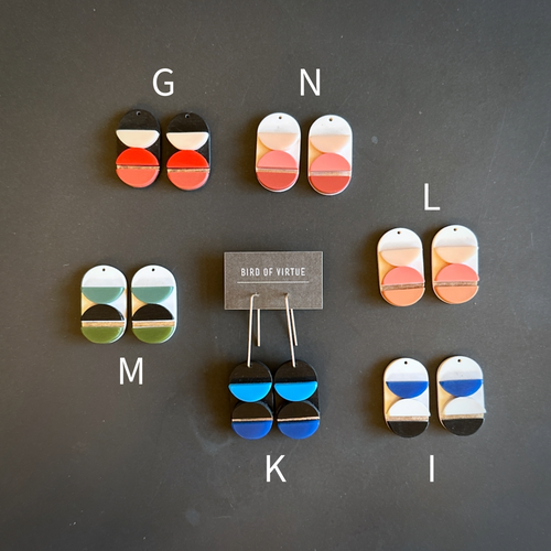 Colorful earrings displayed on a dark surface with 'Bird of Virtue' branding.