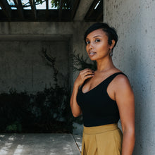Dark skinned woman wearing black tank top and bronze circle earring 
