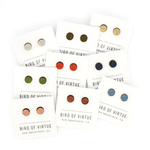 Assortment of colorful circle-shaped wooden stud earrings on white Bird of Virtue cards against a white background. Colors are silver, moss, gold, leaf, poppy, midnight, dogwood, rouge, sky blue