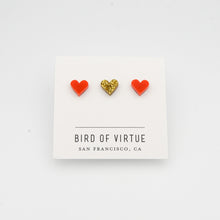 white background with red and gold heart shaped stud earrings on white card
