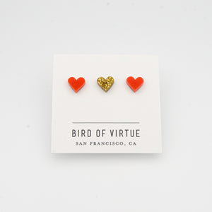 white background with red and gold heart shaped stud earrings on white card
