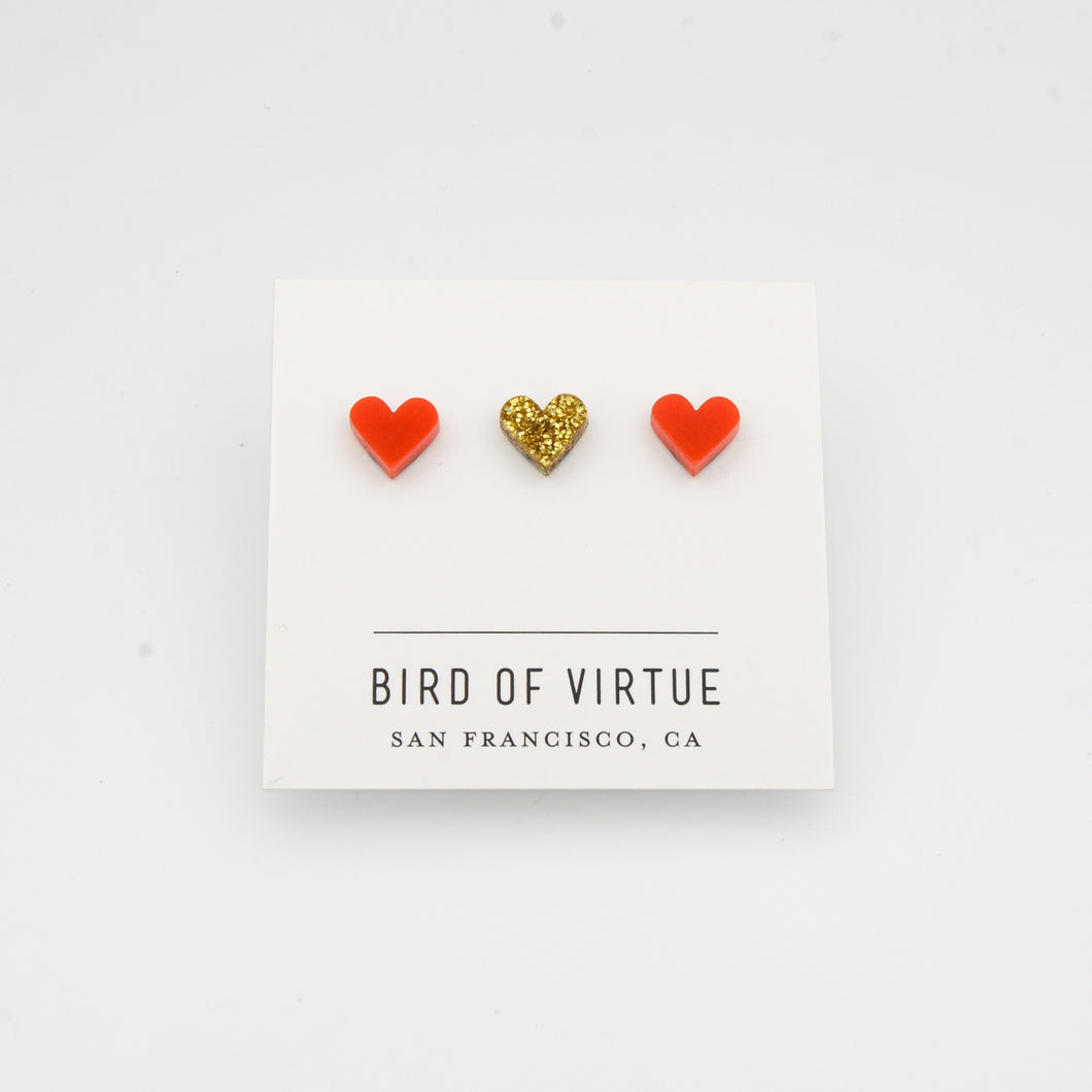white background with red and gold heart shaped stud earrings on white card
