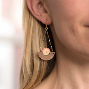 Model wearing walnut wood chandelier earring in coral with bronze centers by Bird of Virtue