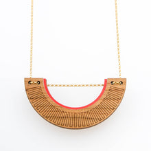 U-shaped gold chain necklace made of cherry wood, with band of red along top and chain running through the piece at the top of the U shape.